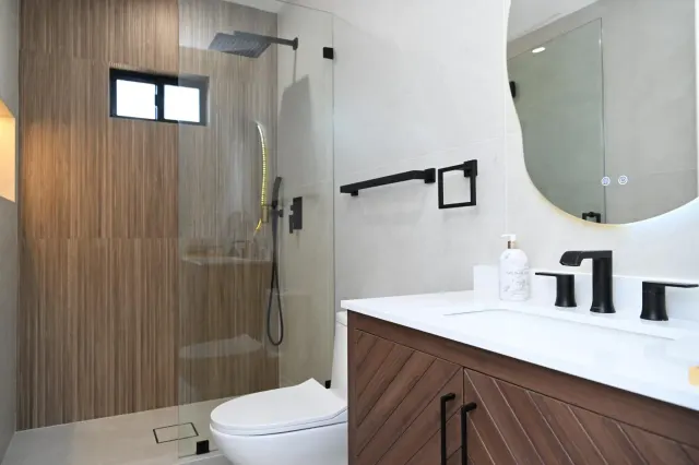 Walk-in shower with wood-look accent wall, black fixtures and floating vanity