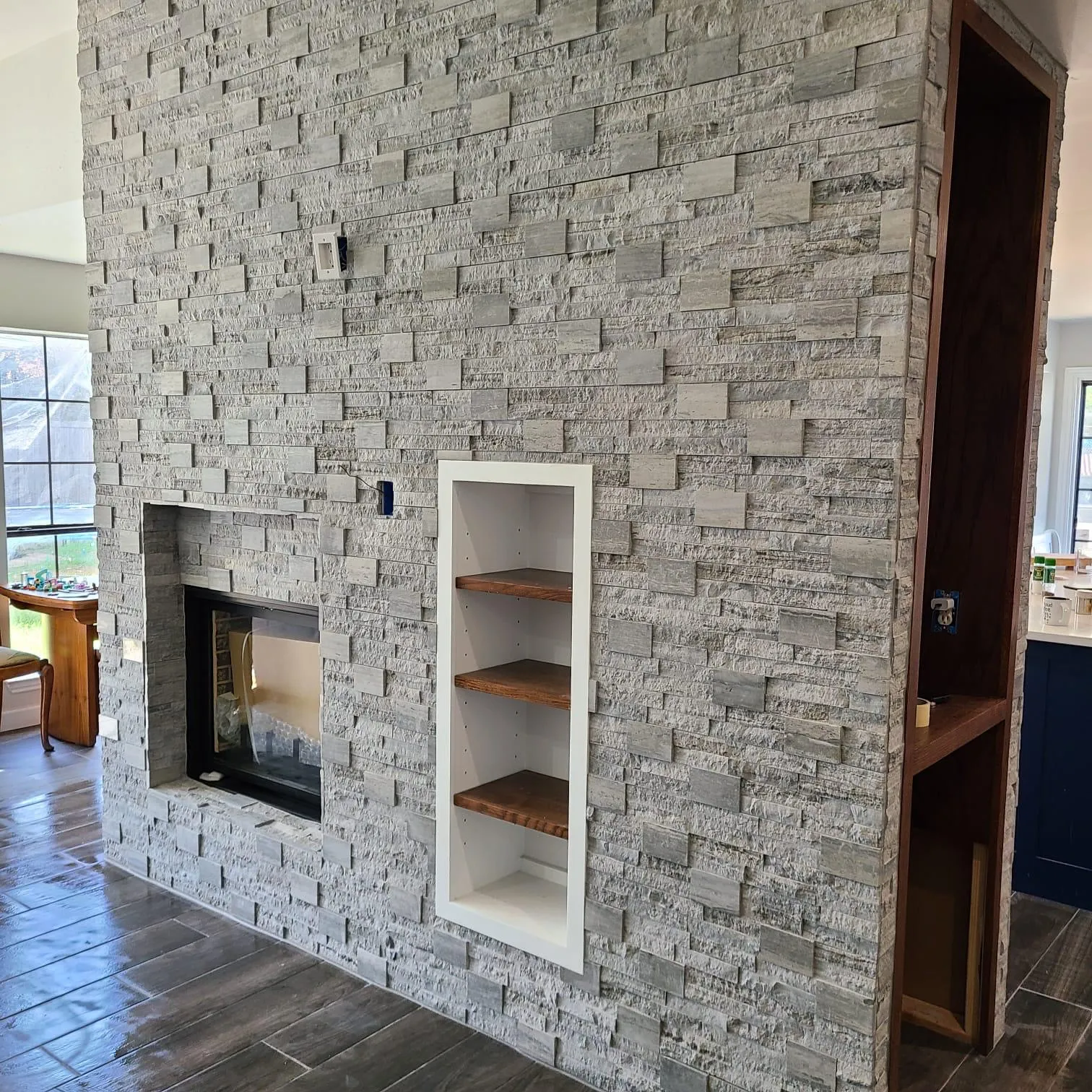 Stone fireplace wall with recessed wood shelving