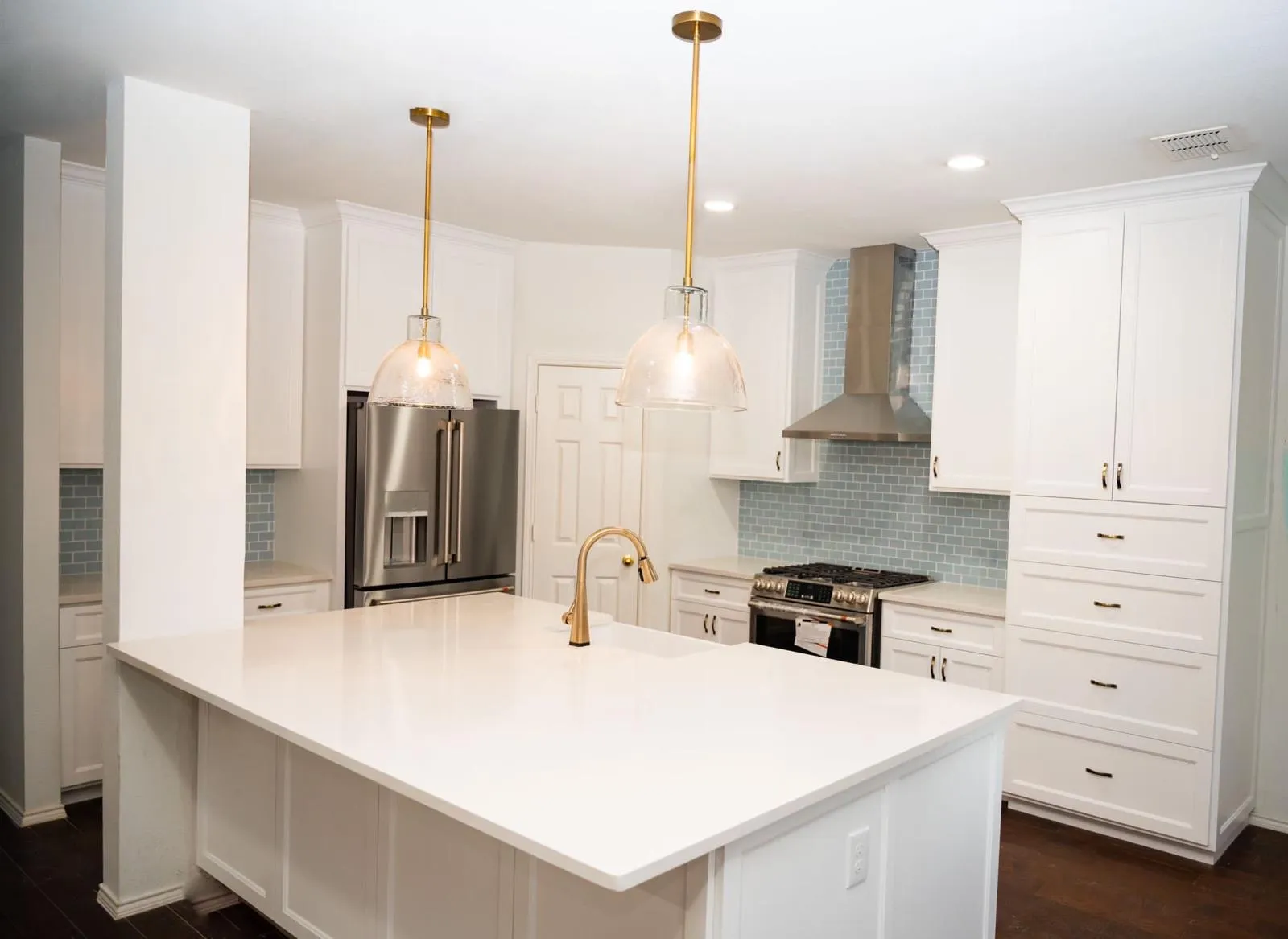 White kitchen remodel with quartz island and gold pendant lights