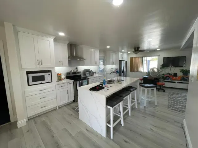 Open-plan white kitchen with waterfall island and bar seating