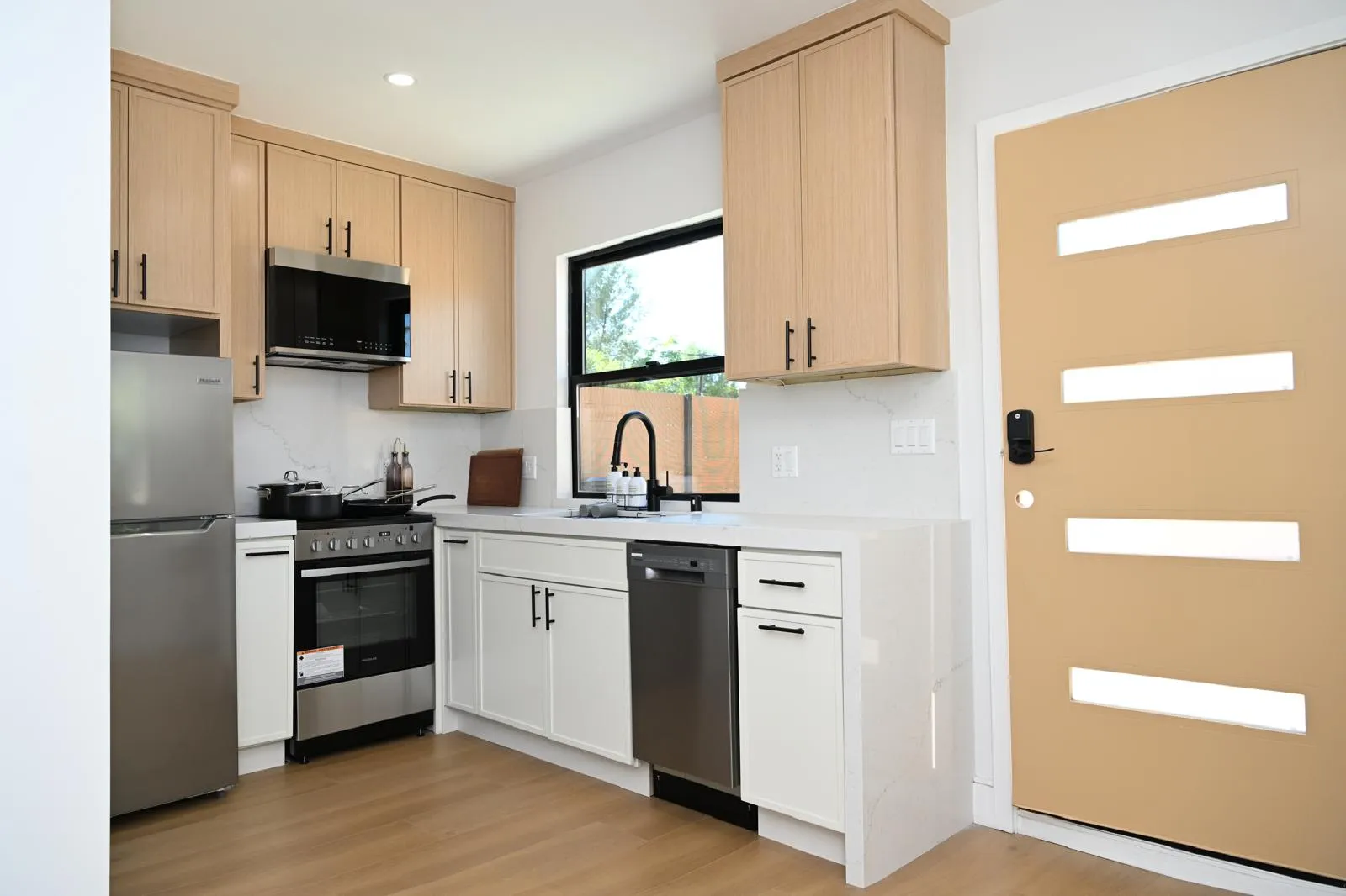 Compact kitchen with light wood cabinets and white quartz counters